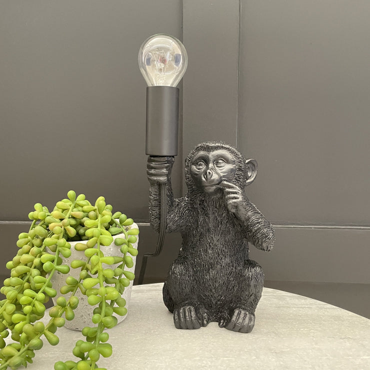 Black baby monkey lamp holding a bulb