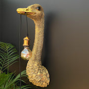 Gold ostrich bird wall lamp with a bulb hanging out of its mouth