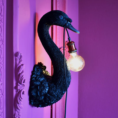 Black swan bird wall light with the light hanging out of it's mouth
