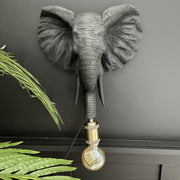 Black elephant head wall light with a bulb out it's trunk