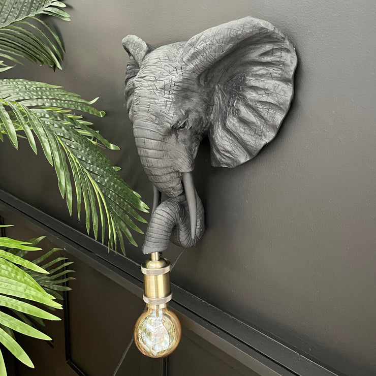 Black elephant head wall light with a bulb out it's trunk