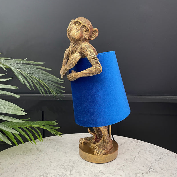 Gold monkey table lamp with a electric blue velvet lampshade around its body