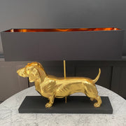Gold sausage dog table lamp with a black rectangular lamp shade